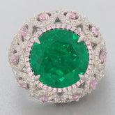 Round green emerald ring with pink accents set in intricate sterling silver design.